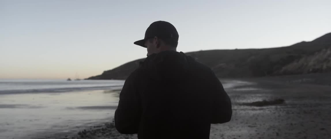 Man stands on a beach at sunset