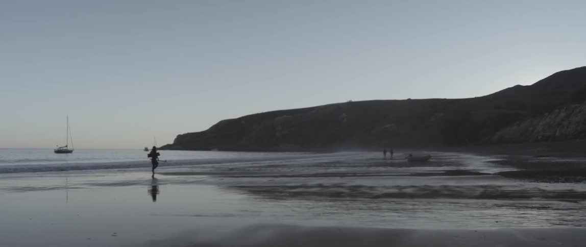 A person is walking on the beach at sunset