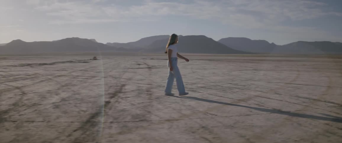 A woman in baggy pants walking straight in a deserted region