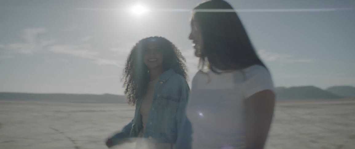 Two women walk across desert on sunny day
