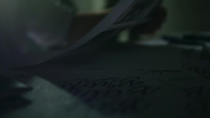 Closeup of hands picking up a paper from a table