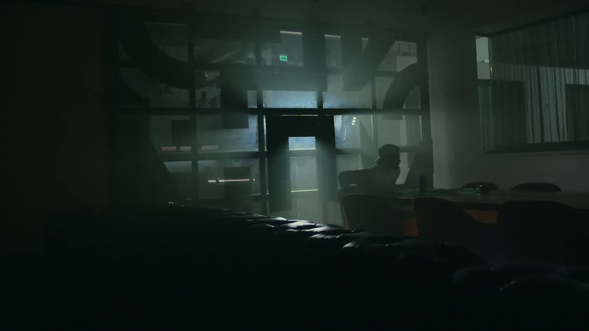 Person enters dark room sits at backlit table