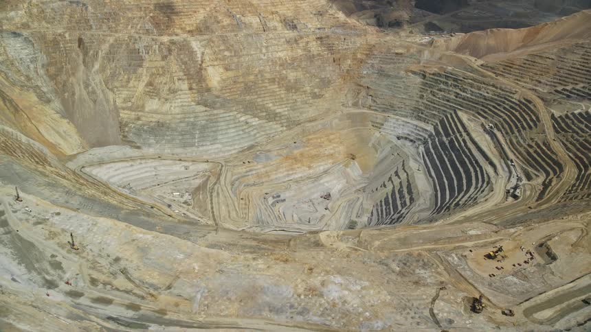Aerial view of gravel haulers at Bingham Copper Mine in Utah as the camera pans left and flies away