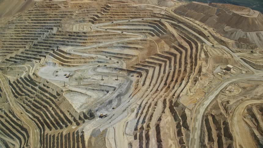 Aerial footage capturing the Bingham Canyon Mine in Utah showing terraced gravel beds and roadways on a sunny day