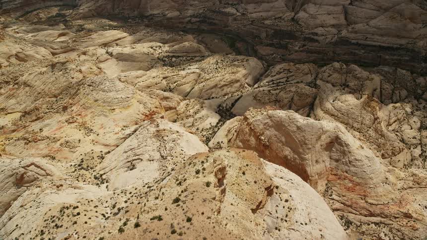 Fly over the mesa and tilt down to capture the breathtaking Waterpocket Fold rock formations of Capitol Reef National Park in Utah during summer