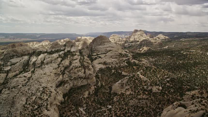 Approach and fly over the stunning Waterpocket Fold rock formations and canyons in Capitol Reef National Park Utah showcasing the breathtaking Southwest desert landscape during a partly cloudy summer day