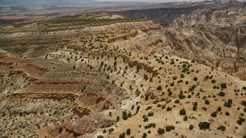 Aerial footage of mesas and mountains in Capitol Reef National Park Utah with red rock canyons and trees growing among the layered bands captured during a sunny summer day