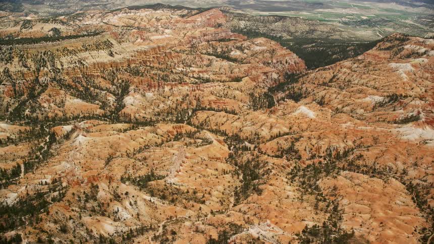 an aerial view of the hills hoodoos and mesa surrounding Bryce Canyon National Park in Utah during summertime