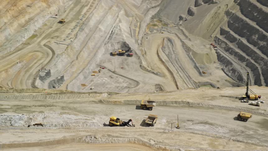 Aerial footage showcasing gravel haulers orbiting around the open pit of Kennecott Copper Mine in Bingham Canyon Utah during a sunny day in summer