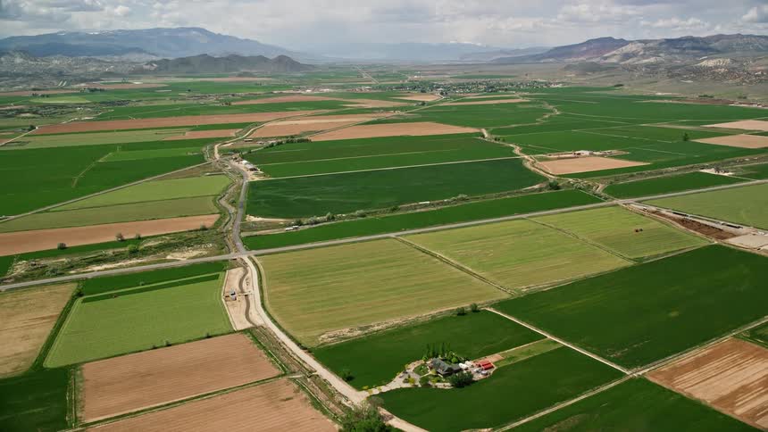 Aerial view of farmland with green fields separated by roads in Aurora Utah during the summer