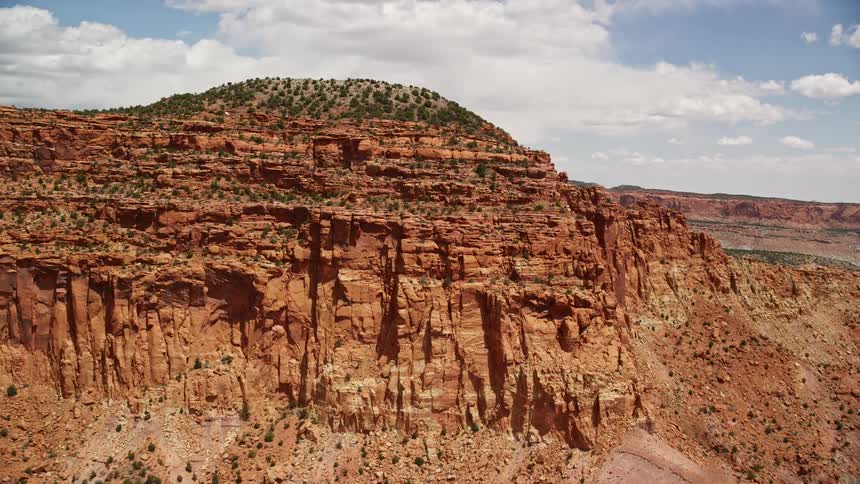 Aerial footage of an orbiting butte topped with trees in Capitol Reef National Park Utah showcasing the arid desert landscape during summer