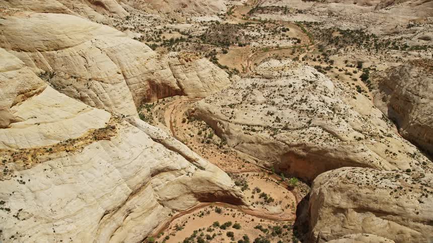  aerial footage capturing an orbit around the twisting canyon of Waterpocket Fold rock formations in Capitol Reef National Park Utah under partly cloudy skies during summer