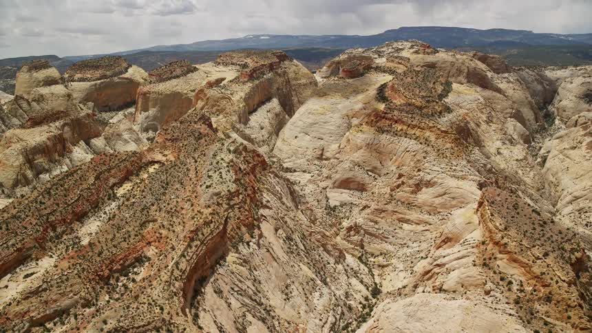  aerial footage captures a stunning pan across and flyby of the canyons in Waterpocket Fold rock formations at Capitol Reef National Park showcasing the arid desert landscape of Utah during the summer