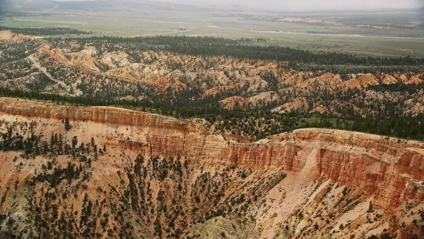 Aerial view of steep mesa slopes trees and desert vegetation passing by in Bryce Canyon National Park Utah on a bright sunny day