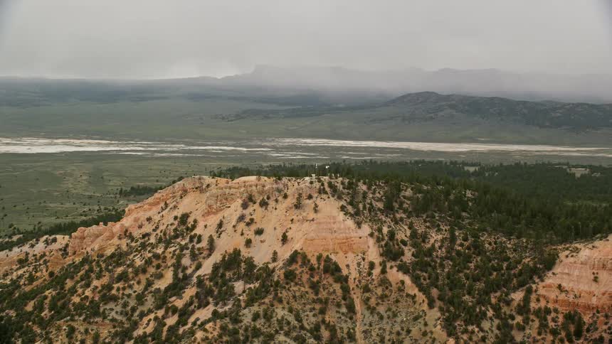 Aerial footage of flying by radio towers on a ridge with a dry lake in the background capturing the scenic beauty of Bryce Canyon National Park in Utah