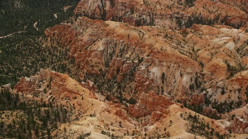 Aerial footage of flying over buttes and canyon in Bryce Canyon National Park Utah showcasing the desert vegetation and stunning landscape