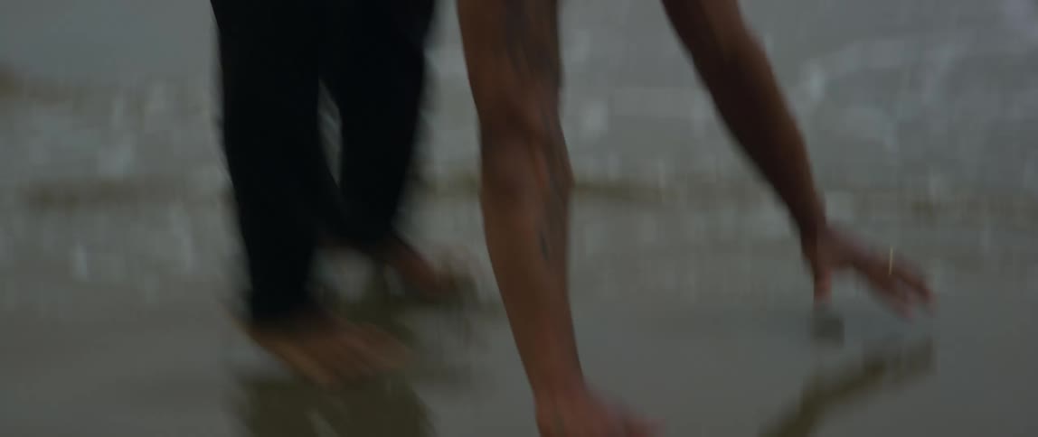 Man exercises on wet beach sand as waves roll onto beach nearby