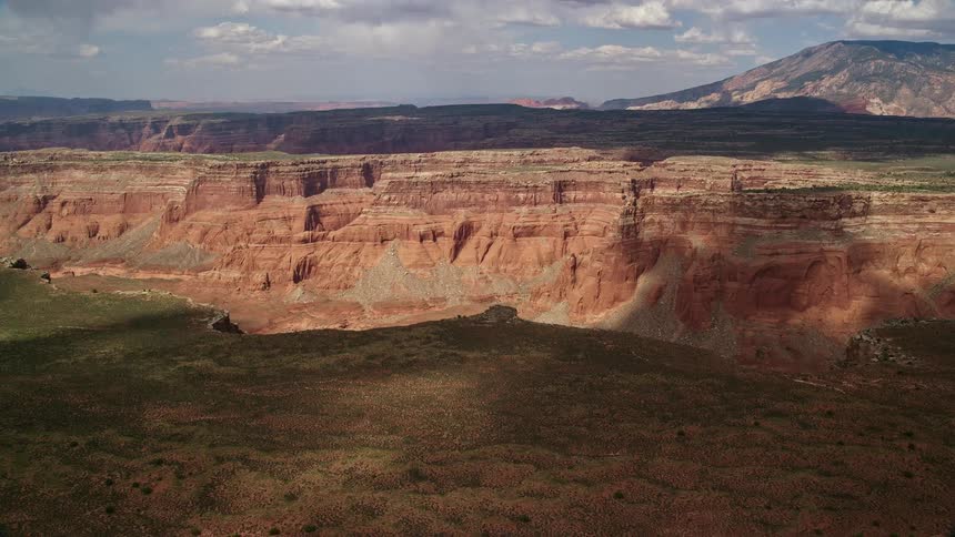 Approaching an expansive wide canyon and distant mesa in the Navajo Nation Reservation Utah with partly cloudy skies and an desert landscape in the Southwest United States during summer