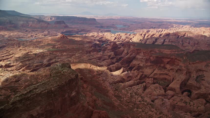 Aerial footage of rock formations in a canyon on the Navajo Nation Reservation in Utah capturing the wide view of the scenic landscape under partly cloudy skies during the summer