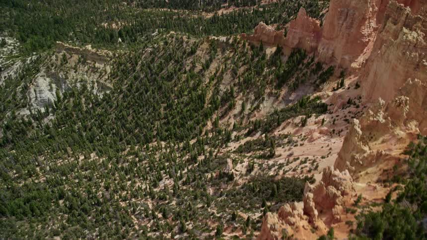  aerial footage showcasing the breathtaking bird's eye view of Pink Cliffs tree-lined canyons and red rock formations in Bryce Canyon National Park Utah during a partly cloudy day