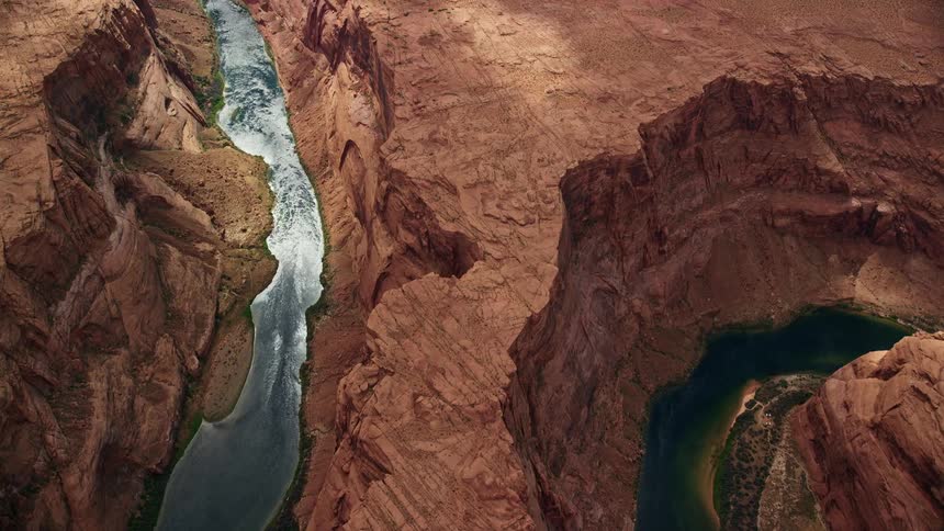 Aerial footage of Horseshoe Bend in Glen Canyon Arizona showcasing the stunning view of Colorado River and the arid desert landscape during a partly cloudy day in Utah