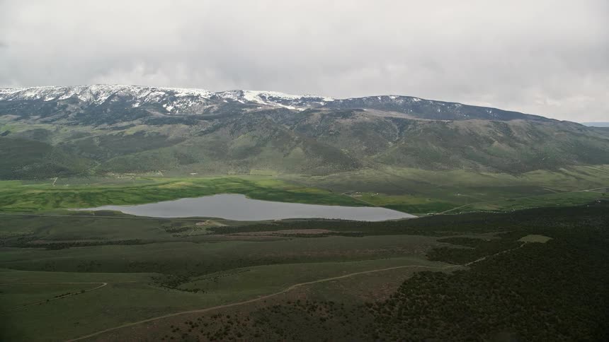 Aerial view of Koosharem Reservoir surrounded by snowy mountains in Fishlake National Forest Utah