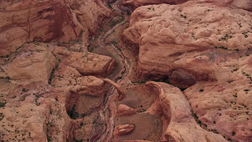 an aerial view of a stone bridge and dry riverbed in Rainbow Bridge National Monument Utah captured during a sunny day in the Southwest United States