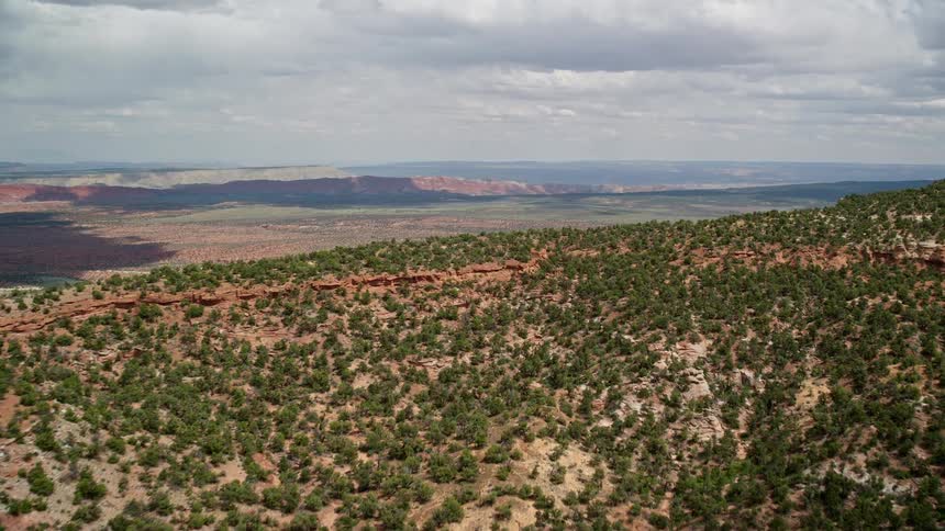 Aerial footage of approaching hills and a wide valley in the Glen Canyon National Recreation Area Utah and Arizona captured on a partially cloudy day during summer in the southwest United States