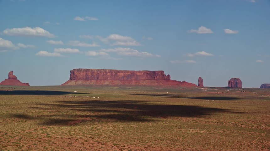 Approaching Sentinel Mesa in Monument Valley Arizona with nearby buttes on a sunny day in the Southwest United States capturing the natural desert landscape of the famous landmark