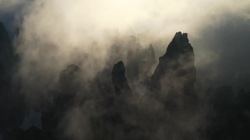 The jagged mist shrouded peaks of a mountain ridge in the evening