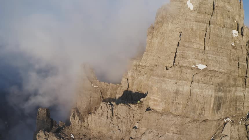 An aerial view of a rocky mountain with snow on a winter day