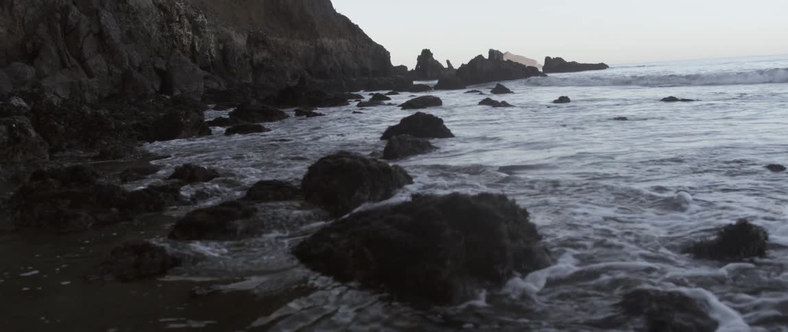 Ocean waves flow around rocks on a beach