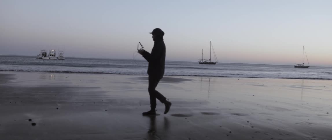 A man is walking along the sand of a beach
