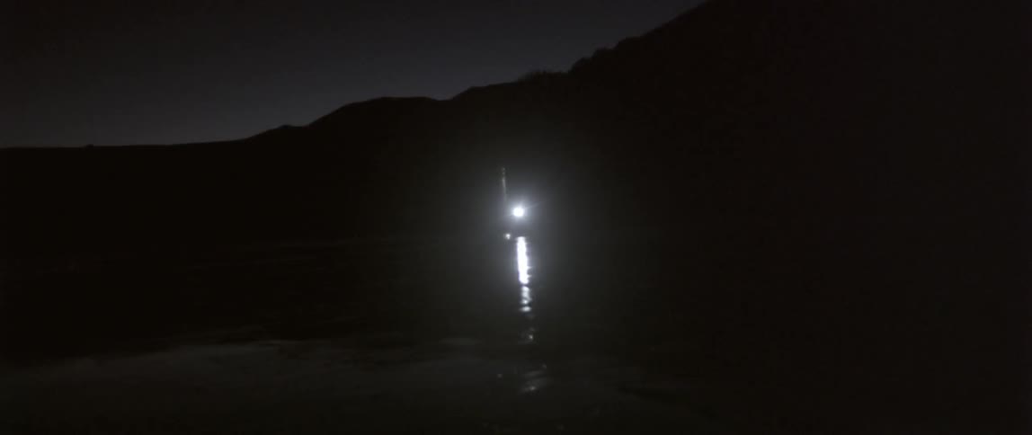 A single light is shining in the distance of a dark area