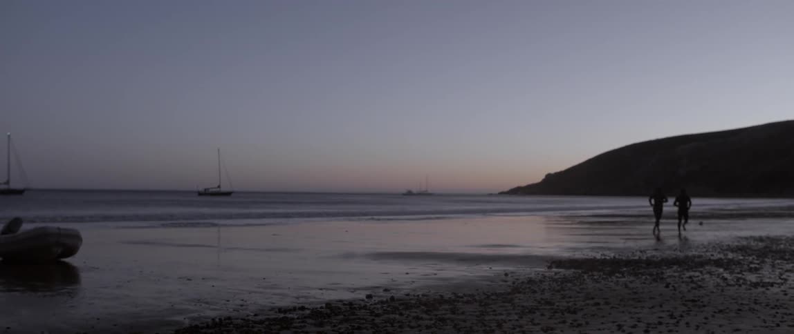 Two people run along the beach at dawn
