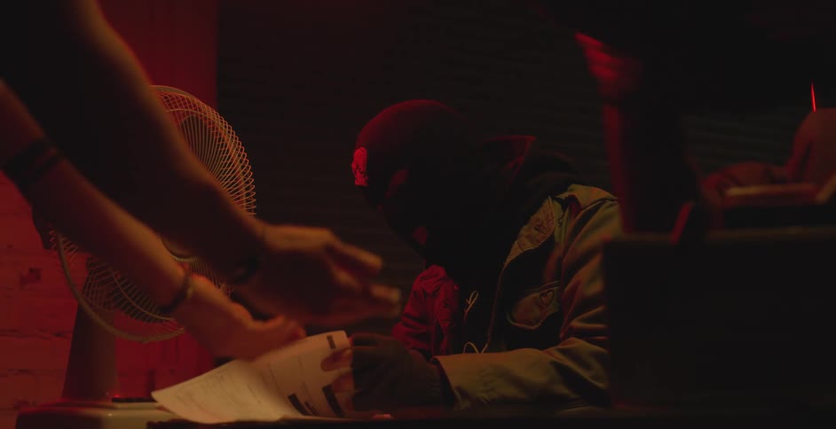 A masked man served people in a dark room with a red light