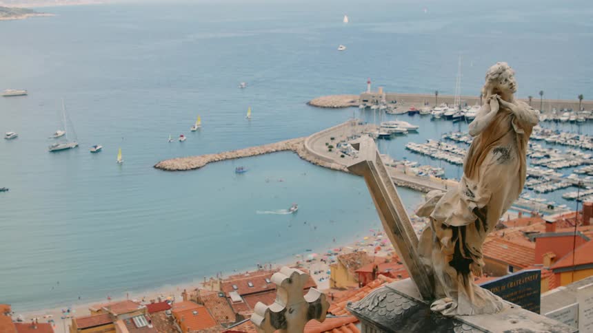 Classically styled statue overlooks beachside buildings and marina