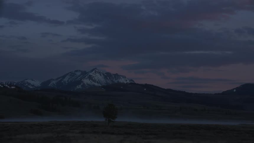 A small lake in the landscape with snowy mountains during dusk