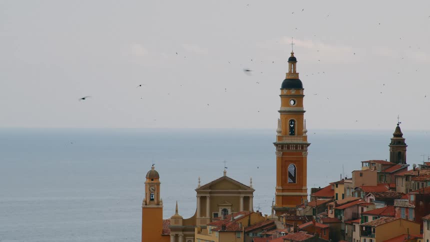 Skyline of a coastal mediterranean city with a large bell tower at the center