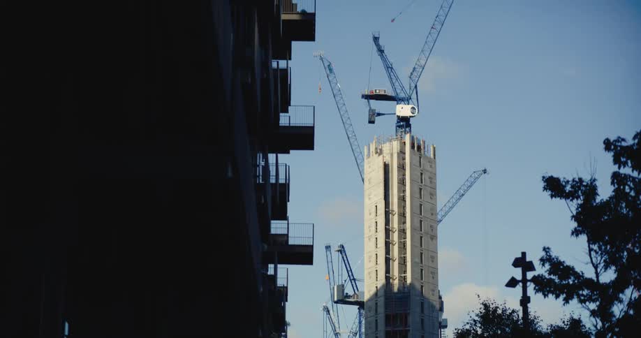 Cranes surrounding sky scraper being built near block of flats in London