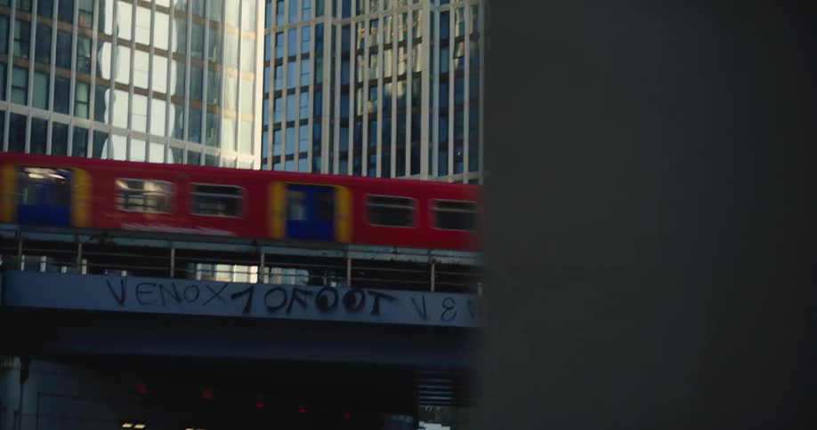 Train travelling over bridge in busy London with skyscrapers behind