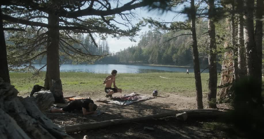 Man squats outside near the woods with a fishing pole