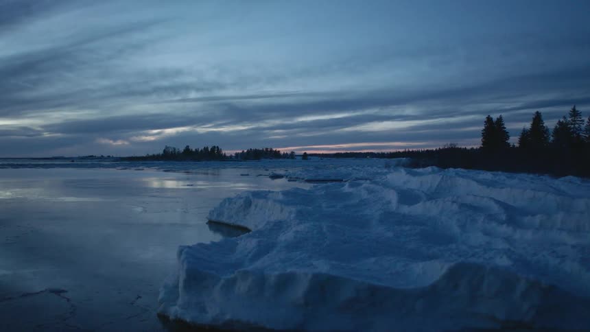 The ice lines the water by the shore