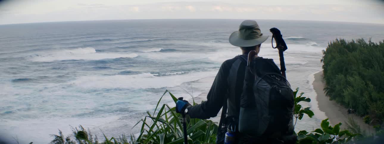 A man hikes to the edge overlooking the ocean