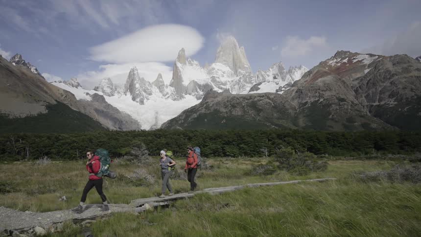 Three people jogging on a path in a field next to mountains