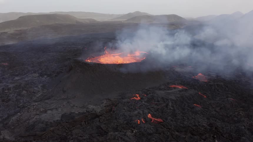 Lava smokes and bubbles in a volcano during the day