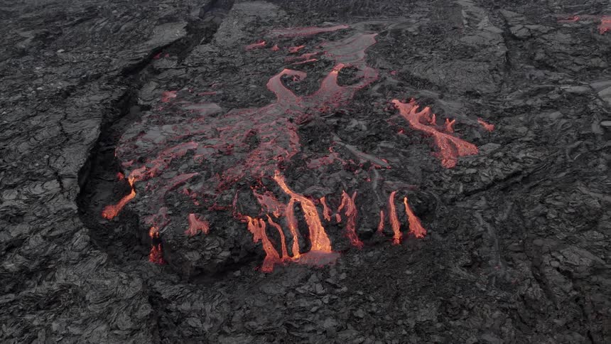 Aerial view of lava leaking from a rocky crater and magma