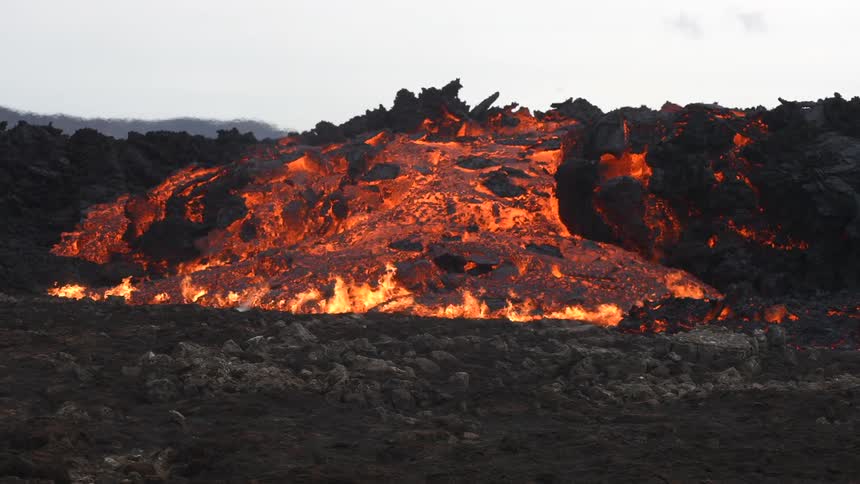 Closeup of an erupting volcano and a lava river