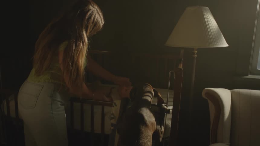 Baby in the crib and the mother caressing her infant with a dog standing beside observing