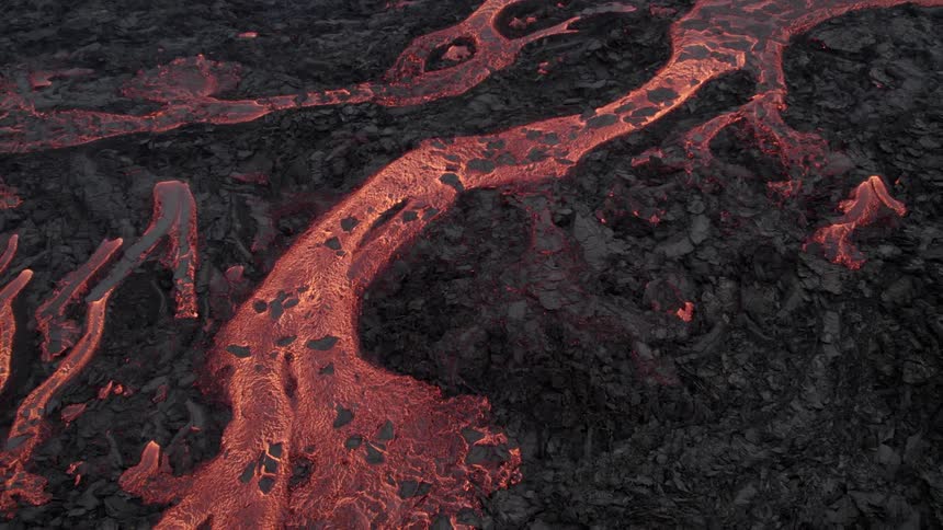 Aerial view of lava flow over the black rocky soil on an active volcano